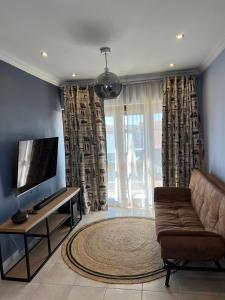 ein Wohnzimmer mit einem Sofa und einem Flachbild-TV in der Unterkunft Relaxing Getaway in Waterfall - close to Mall of Africa in Midrand