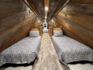 two beds in a room with wooden walls at Serendib by St Peters Bay in Saint Peters
