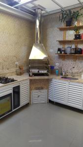 uma cozinha com armários brancos e um forno com placa de fogão em Casa na Praia de Maitínga - Bertioga - SP em Bertioga