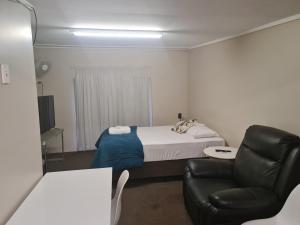 a bedroom with a bed and a desk at Kalua Motel in Bundaberg