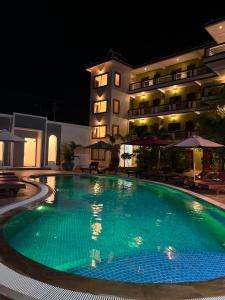a swimming pool in front of a hotel at night at The Moon Kampot Boutique in Kampot