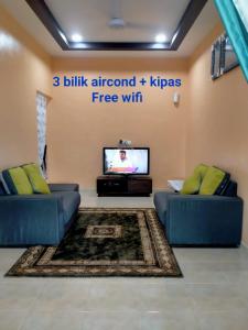 sala de estar con 2 sofás azules y TV en Rahman Homestay Pantai Johor - ISLAM SAHAJA, en Alor Setar