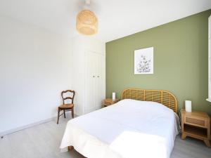 um quarto com uma cama branca e uma cadeira em Maison Ars-en-Ré, 3 pièces, 4 personnes - FR-1-434-101 em Ars-en-Ré