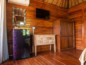 a living room with a tv and a wooden wall at Pondok Biu in Denpasar