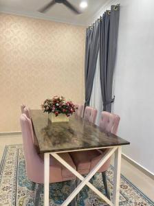 a dining room table with pink chairs and flowers at 13StayCation Islamic Homestay in Melaka
