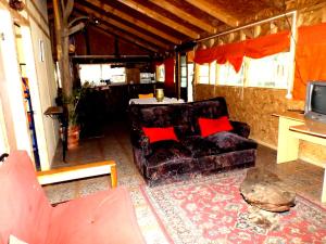 sala de estar con sofá y almohadas rojas en Cabañas Aguas Claras, en Pinto