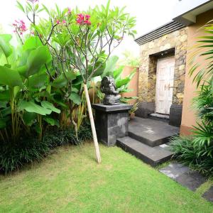 a statue of a cat sitting on a bench in a garden at Surya Guest House Sanur in Sanur