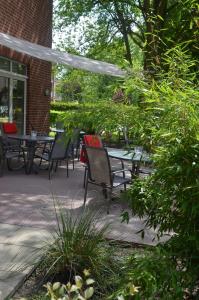 un patio con sillas, mesa y árboles en Hotel Aquamarin, en Papenburg