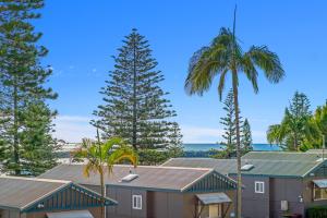 a row of houses with palm trees and the ocean at Crystal Waters 2 2 Munster Street in Port Macquarie