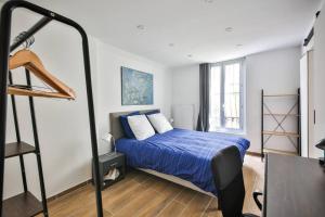 Un dormitorio con una cama con sábanas azules y una escalera en Le Nid de Montmartre, en París