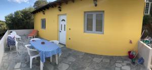 a yellow house with a table and chairs on a patio at Anna’s Olive Grove in Ammouliani