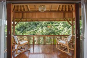 two chairs on a porch with a view of the forest at Giriwood Hotel & Villa in Bedugul