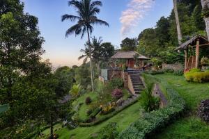 a garden with a house and a palm tree at Loids Villa Eco Lodge Lempuyang in Seraya