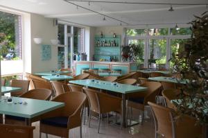a restaurant with tables and chairs and windows at Hotel Aquamarin in Papenburg