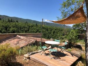a table and chairs on a wooden deck with a hammock at Logement calme avec vue sur le Luberon in Saignon