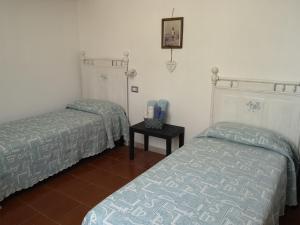 ein Schlafzimmer mit 2 Betten und einem Tisch darin in der Unterkunft Ghiramonte, vita in campagna a due passi dal mare in Siniscola