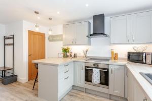a kitchen with white cabinets and a stove top oven at Eames Cottage in Cowling