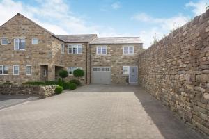a large brick house with a stone wall at Eames Cottage in Cowling