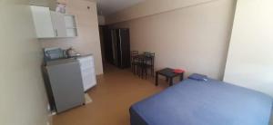 a room with a bed and a refrigerator and chairs at A’s Condo in Iloilo City