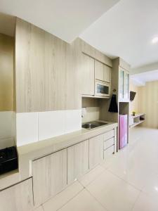 a kitchen with white cabinets and a refrigerator at Hozby Skyview Setiabudi in Sunggal