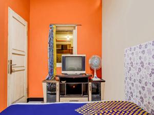 a bedroom with a tv and an orange wall at SPOT ON 91186 Losmen Yanti in Bandung