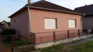 une maison rose avec une clôture devant elle dans l'établissement Kuća za odmor Balera, 