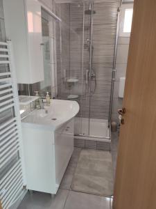 La salle de bains blanche est pourvue d'un lavabo et d'une douche. dans l'établissement Kuća za odmor Balera, 