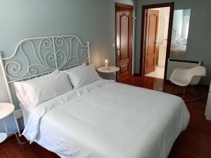 Schlafzimmer mit einem großen weißen Bett mit blauem Kopfteil in der Unterkunft Rodeira in Cangas