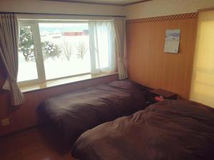 a bedroom with a bed next to a window at Other Side House in Nakafurano