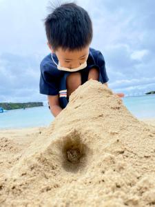 a young boy is playing in the sand on the beach at Onna Japanese Style Hotel Hokkaisou in Onna