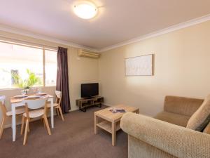 uma sala de estar com uma mesa, um sofá e uma televisão em Villa Nova Motel em Toowoomba
