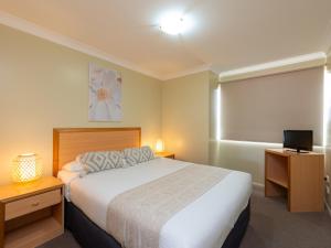 a hotel room with a bed and a television at Villa Nova Motel in Toowoomba