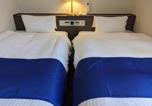 dos camas sentadas una al lado de la otra en una habitación en Ichinomiya City Hotel, en Ichinomiya