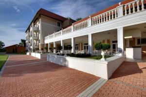 a large white building with a brick sidewalk at Arcanum Hotel in Békéscsaba