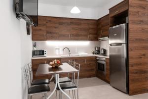 una cocina con armarios de madera y una mesa con sillas. en Dinos Apartments, en Vasiliki