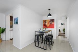 Un comedor con mesa y taburetes en El Olivia on Genoa, en Gold Coast