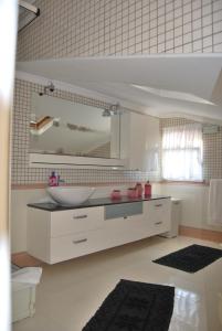 a white bathroom with a sink and a mirror at Apartamentos 7 saias in Nazaré