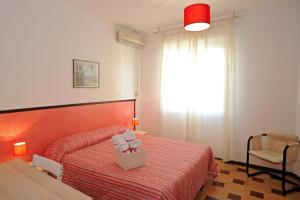 a bedroom with a red bed and a chair and a window at Appartamento Parco Tarragona in Alghero