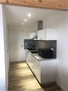 a kitchen with white cabinets and a microwave at Casa di lise e bastien in San-Nicolao