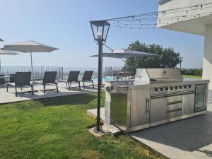 uma grelha num quintal com cadeiras e um guarda-sol em Open Land Holiday Suite em Piedimonte Etneo