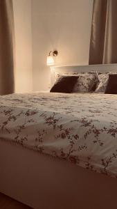 uma cama com um edredão branco com flores em Apartament Vintage em Mrągowo