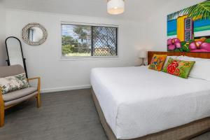 ein Schlafzimmer mit einem Bett, einem Stuhl und einem Fenster in der Unterkunft A Touch of the Bahamas on McKenzie MK3 in Cairns