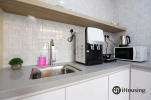 a kitchen counter with a sink and a microwave at The Quartz Melaka By I Housing in Melaka
