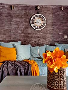 eine Couch mit einer Uhr und eine Vase mit orangefarbenen Blumen in der Unterkunft Hapilis in Alexandroupoli