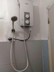 een douche in een badkamer met een witte slang bij Bogah Lodge in Banaue