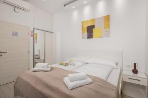 a white bedroom with two beds with towels on them at Lux Apartments in Rijeka