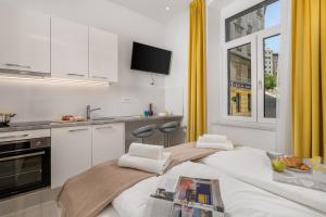 a white kitchen with two beds and a window at Lux Apartments in Rijeka