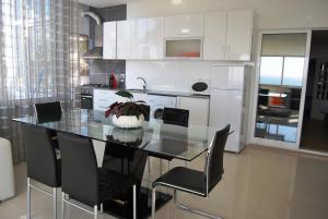 a kitchen with a glass table and black chairs at Apartamentos 7 saias in Nazaré +11 photos
