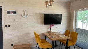 a dining room with a wooden table and yellow chairs at Domki Mili Lubie Gudowo Jezioro Lubie in Drawsko Pomorskie