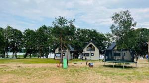 a small house with a playground in front of it at Domki Mili Lubie Gudowo Jezioro Lubie in Drawsko Pomorskie